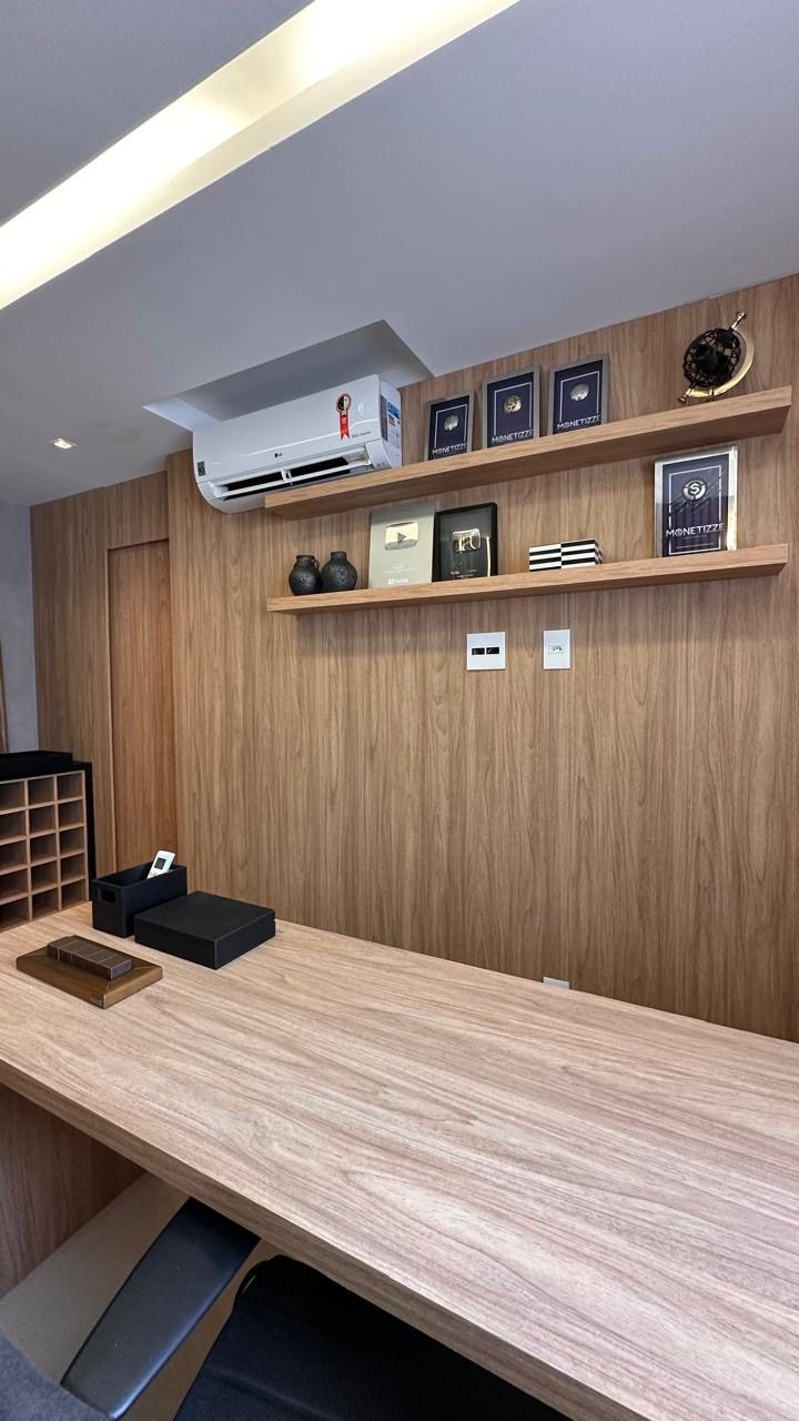 Mesa de trabalho em madeira com prateleiras suspensas e quadros emoldurados na parede
